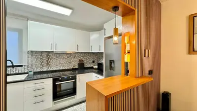 a kitchen with white cabinets and a wooden counter top at The North Paradise - Porto Moniz in Porto Moniz