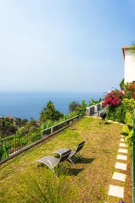 two chairs sitting on the grass in a yard at Meerblick - Exklusives Loft mit Terrassen & Hot-Tub in Fajã da Ovelha