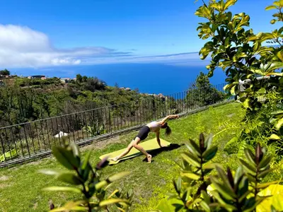 a woman doing a yoga pose on the side of a hill at Meerblick - Exklusives Loft mit Terrassen & Hot-Tub in Fajã da Ovelha