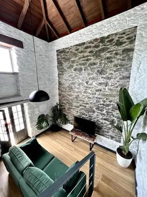 a living room with a couch and a stone wall at Meerblick - Exklusives Loft mit Terrassen & Hot-Tub in Fajã da Ovelha