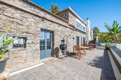 a patio of a stone house with a table and chairs at Meerblick - Exklusives Loft mit Terrassen & Hot-Tub in Fajã da Ovelha