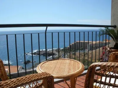 a balcony with a table and chairs and the ocean at Magos Sunrise - Apt with sea view in Caniço