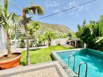 a backyard with a swimming pool and palm trees at Casa das Amoreiras by YMR in Arco da Calheta
