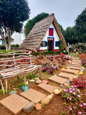 a small house with a thatched roof in a garden at Forum Ocean View Apartment 2 in Funchal