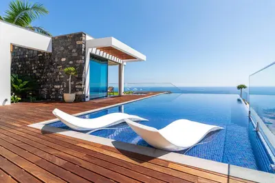 a swimming pool with two white chairs on a house at Refúgio na Escarpa Luxury Villa in Quinta Grande