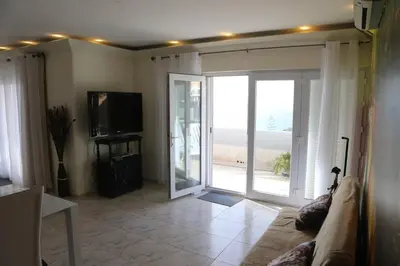 a living room with a couch and a sliding glass door at Penthouse Ventur in Caniço