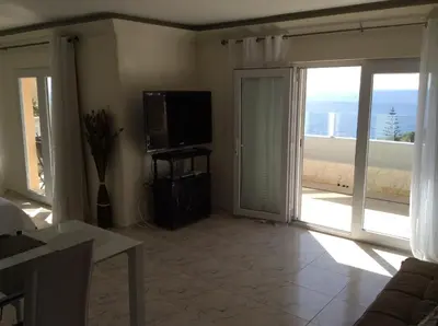 a living room with a television and a sliding glass door at Penthouse Ventur in Caniço