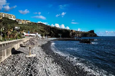 a beach with umbrellas on a rocky shore at Penthouse Ventur in Caniço