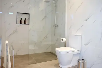 a bathroom with a toilet and a glass shower at Vila Indigo in Arco da Calheta