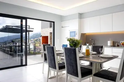 a kitchen and dining room with a table and chairs at Vila Indigo in Arco da Calheta