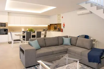 a living room with a gray couch and a kitchen at Vila Indigo in Arco da Calheta