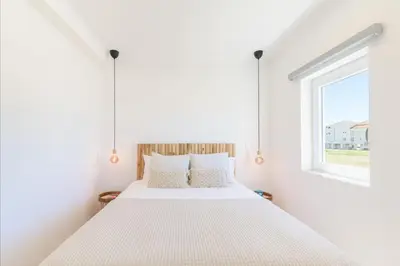 a bedroom with a large white bed with a window at Bela Vista_Cozy Apt With Sea View in Praia da Arrifana