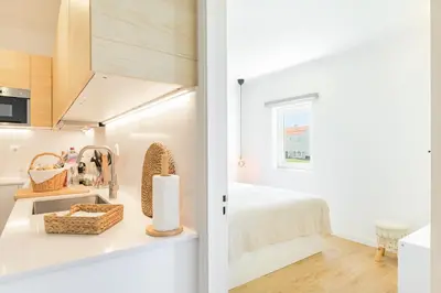 a white bedroom with a bed and a window at Bela Vista_Cozy Apt With Sea View in Praia da Arrifana