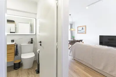 a white bathroom with a toilet and a sink at Bela Vista_Cozy Apt With Sea View in Praia da Arrifana