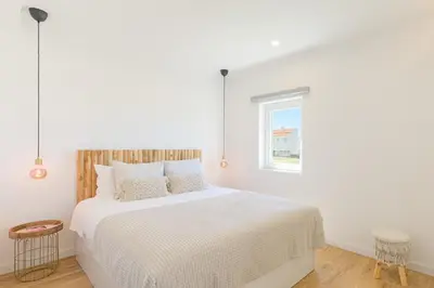 a bedroom with a large white bed with a window at Bela Vista_Cozy Apt With Sea View in Praia da Arrifana