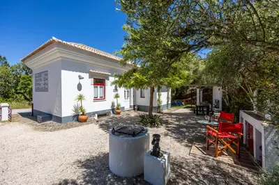 a small white house with red chairs in the yard at Casa dos Cantoneiros in Aljezur