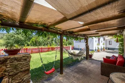 a patio with a hammock under a pergola at Casa dos Cantoneiros in Aljezur