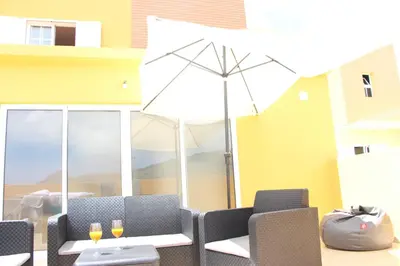 a patio with a table and chairs and an umbrella at Moradia Vitória in Porto Santo