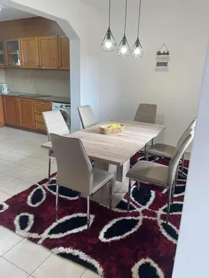 a dining room with a table and chairs on a rug at Moradia Vitória in Porto Santo