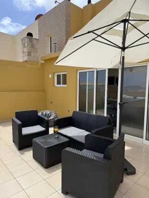 a patio with two couches and an umbrella at Moradia Vitória in Porto Santo