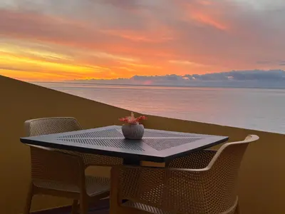 a table and chairs on a balcony with a sunset at Bela Vigia in Jardim do Mar