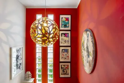 a room with a red wall with a clock and pictures at Bela Vigia in Jardim do Mar