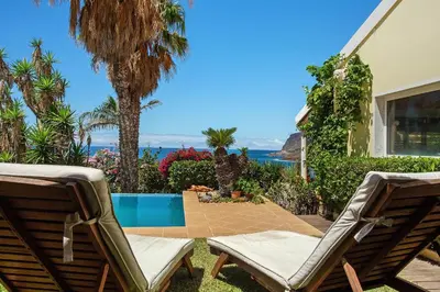 a swimming pool in front of a house with palm trees at Bela Vigia in Jardim do Mar
