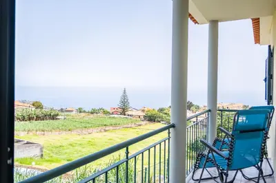 a blue chair on a porch with a view of the ocean at Casa D Agostinha by Homie in Canhas