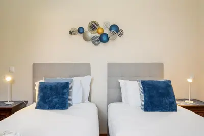 two beds with blue pillows and a clock on the wall at Casa D Agostinha by Homie in Canhas