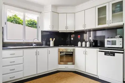 a white kitchen with white cabinets and a microwave at Casa D Agostinha by Homie in Canhas
