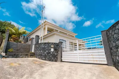 a house with a white garage door and a fence at GuestReady - Spacious stay with sea views in Caniço