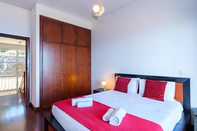 a bedroom with a large bed with red and white pillows at GuestReady - Spacious stay with sea views in Caniço