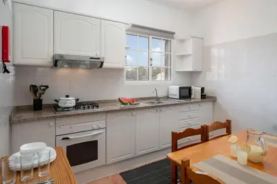 a kitchen with white cabinets and a wooden table at Abelisa by An Island Apart in Porto Santo