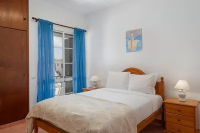 a bedroom with a bed with blue curtains and a window at Abelisa by An Island Apart in Porto Santo