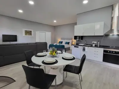 a kitchen and living room with a table and chairs at Lovers Caniço Center in Caniço