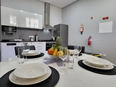 a kitchen with a table with plates and wine glasses at Lovers Caniço Center in Caniço