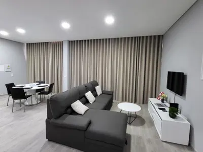 a living room with a black couch and a table at Lovers Caniço Center in Caniço