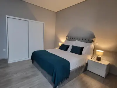 a bedroom with a large bed with a blue blanket at Lovers Caniço Center in Caniço