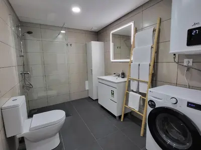 a bathroom with a toilet a sink and a washing machine at Lovers Caniço Center in Caniço