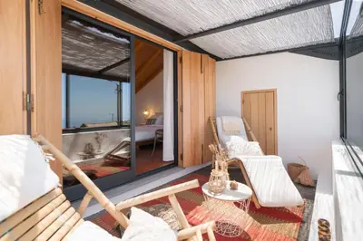 a room with a balcony with chairs and a tub at Casa da Raposeira by An Island Apart in Calheta