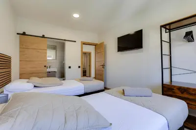 a bedroom with three beds and a tv at Refúgio do Cabo in Sagres