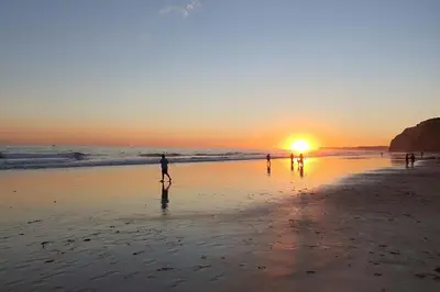 a group of people walking on the beach at sunset at ValMar Ocean and Pool View Apartment in Lagos