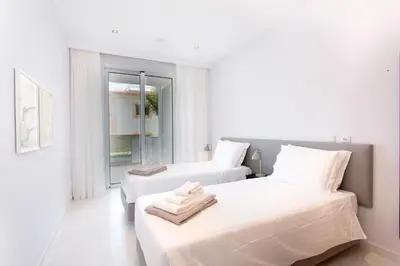 a white bedroom with two beds and a window at ValMar Ocean and Pool View Apartment in Lagos