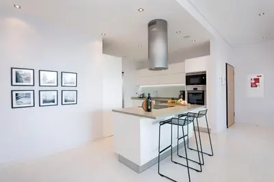 a kitchen with white walls and a counter with stools at ValMar Ocean and Pool View Apartment in Lagos