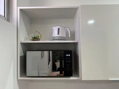 a microwave in a white cabinet with a kettle on top at Oásis Suites - Funchal in Funchal