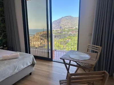 a room with a table and a balcony with a view at Oásis Suites - Funchal in Funchal