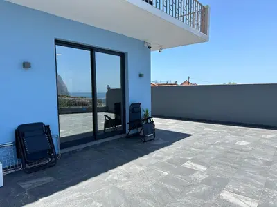 a patio with two chairs on a blue building at Oásis Suites - Funchal in Funchal