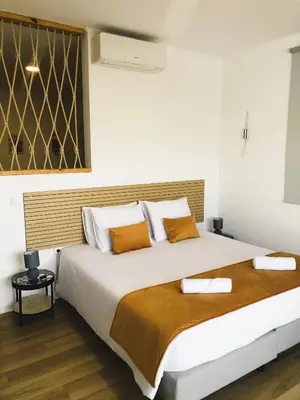 a bedroom with a large white bed with orange pillows at Oásis Suites - Funchal in Funchal