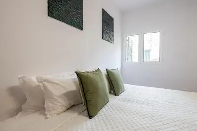 a white bedroom with a bed with green pillows at Casa da Silva home in Funchal in Funchal