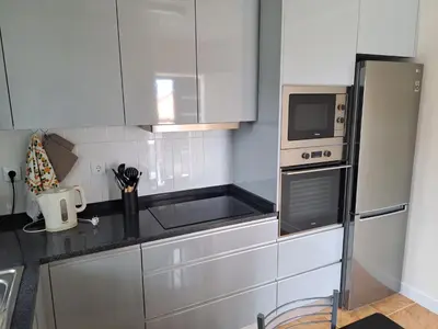 a kitchen with white cabinets and a microwave at Success House in Calheta